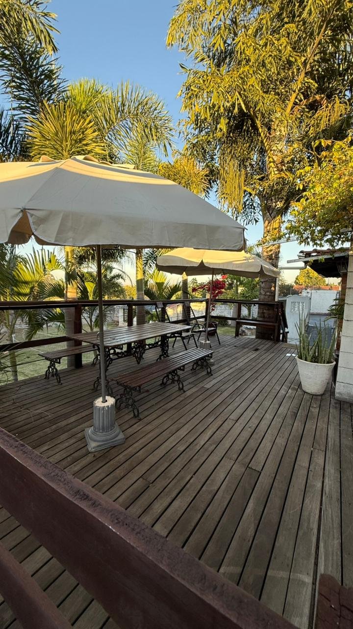 Deck de madeira com guarda-sol e mesas na área de lazer